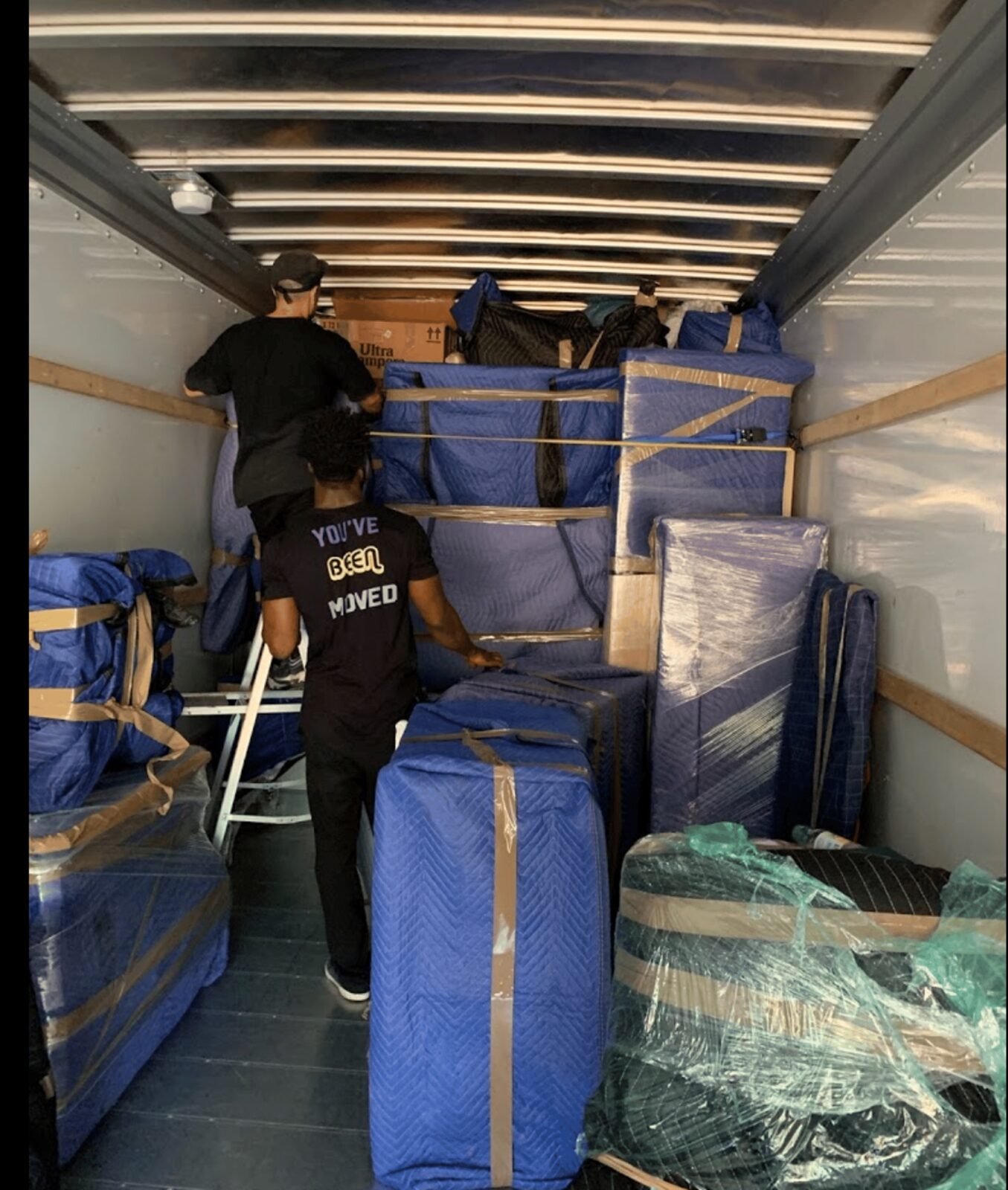 Moving truck interior packed tight with padded furniture and bins